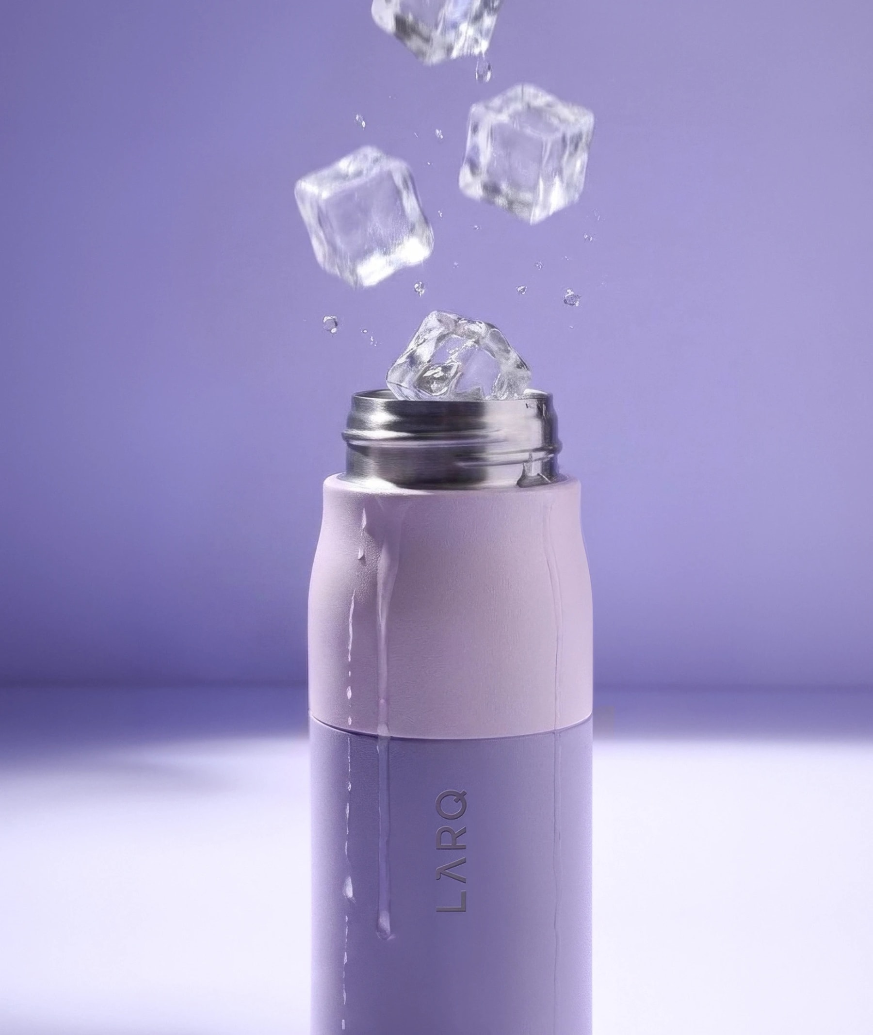 The bottle with its handle and charms on a yoga mat beside lavender dumbbells