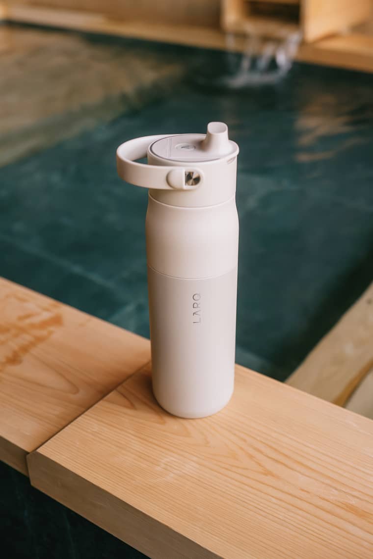 LARQ Bottle PureVis on a wooden ledge beside a landscaped water basin
