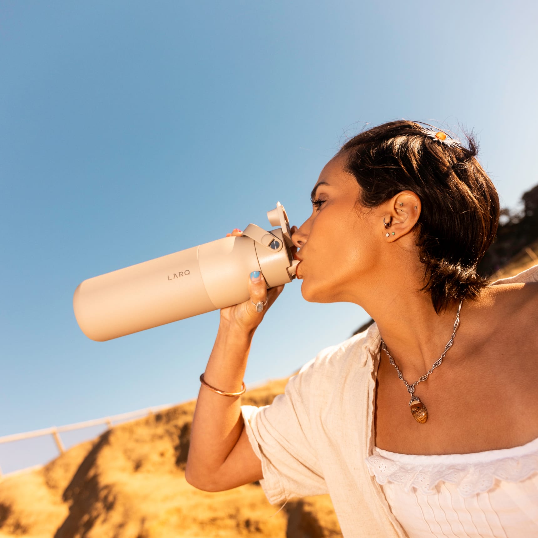 Woman drinking water from Larq bottle twist top granite white